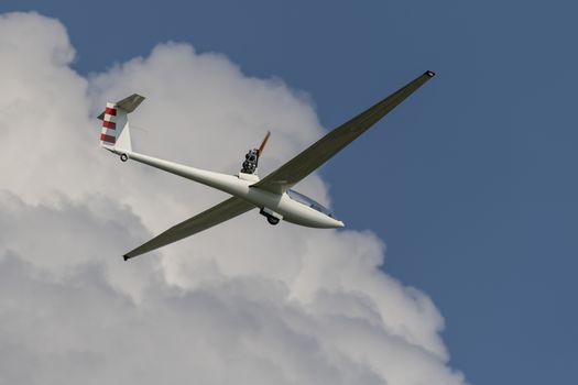 Modern motorized glider in a blue sky with white clouds
