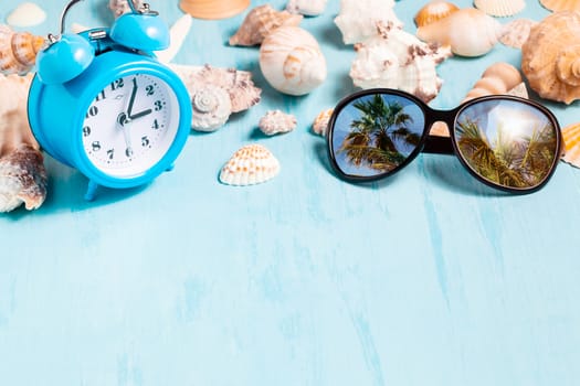 Blue sea background with alarm clocks, sunglasses and seashells, summer holiday and vacation time concept.