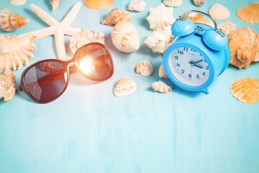 Blue sea background with alarm clocks, sunglasses and seashells, summer holiday and vacation time concept.