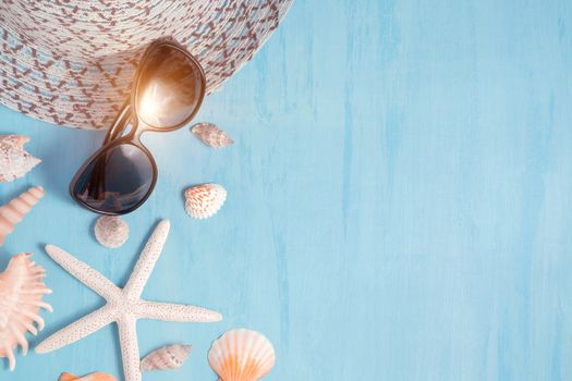 Blue sea background with hat, sunglasses and seashells, summer holiday and vacation time concept.