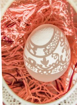 Easter. A beautiful Easter card with an openwork vertical oval frame through which beautiful shadows fall on a white egg. Green background, top view.