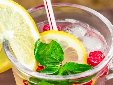 Refreshing summer cocktail with lemon, raspberry and mint close-up.