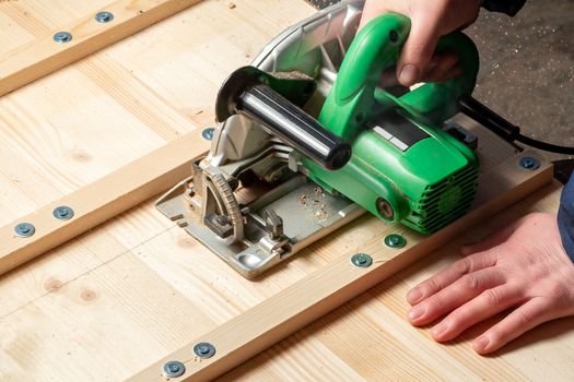 Male hands sawing boards with a circular saw.