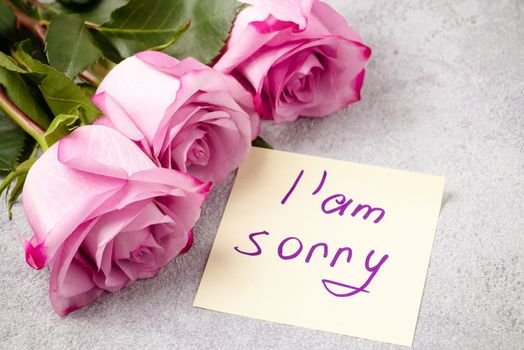 bouquet of pink roses, a heart and a note with the inscription I am sorry on the table-the concept of love and care.