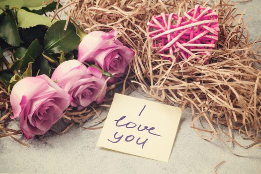 bouquet of pink roses, a heart and a note with the inscription I love you on the table-the concept of love and care.