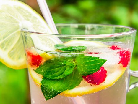 Refreshing summer cocktail with lemon, raspberry and mint close-up.