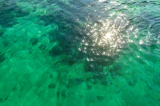 Surface of clear transparent turquoise seawater with small waves.