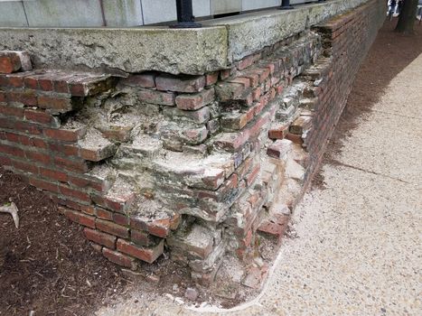 broken or damaged brick wall or masonry with cement sidewalk