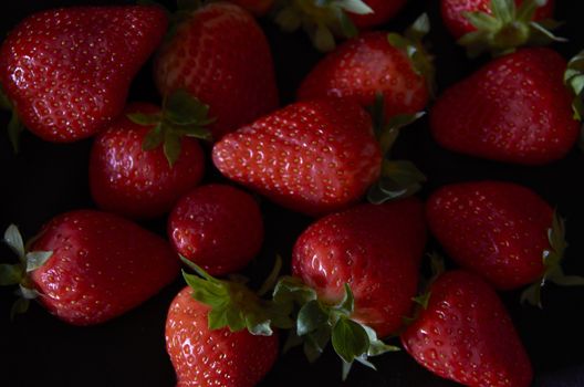 Strawberries on black background, long exposure natural light