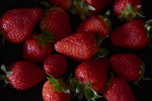 Strawberries on black background, long exposure natural light