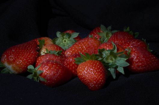 Strawberries on black background, long exposure natural light