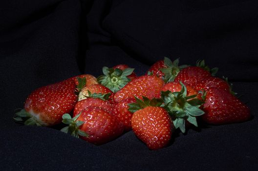 Strawberries on black background, long exposure natural light