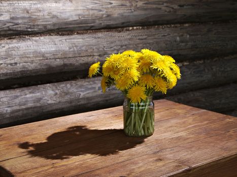bouquet of dandelions in a room with log walls