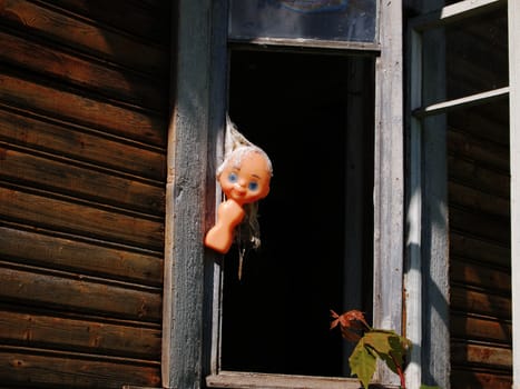 disfigured doll on the window of an abandoned house