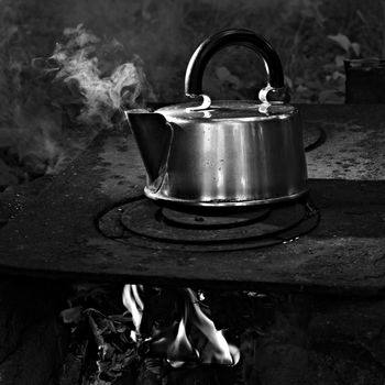 kettle with boiling water on the garden stove, black and white image