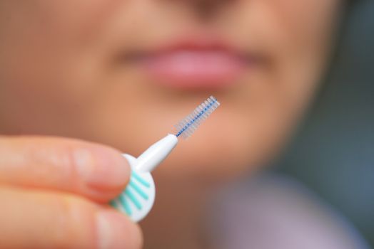 Woman cleaning her teeth with an interdental brush