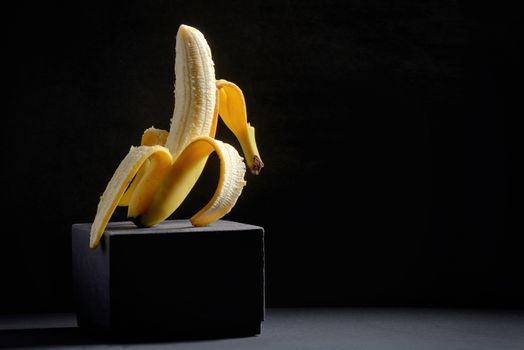 Concept with Half peeled banana on black background