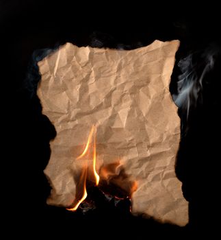 burning piece of crumpled paper on black background