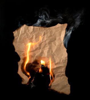 burning piece of crumpled paper on black background