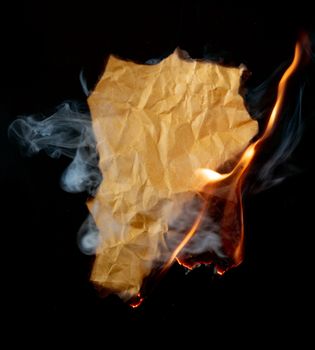 burning piece of crumpled paper on black background