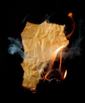 burning piece of crumpled paper on black background