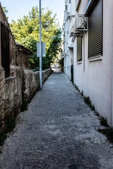 a narrow urban street with stone floors and old vintage buildings. photo has taken at foca/izmir.