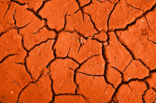 Dry crackinged land of the red colour in arid desert
