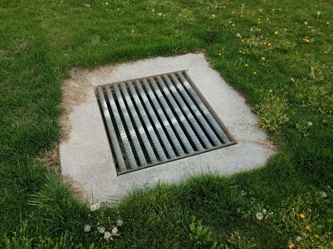 drain with metal grate bars and green grass or lawn