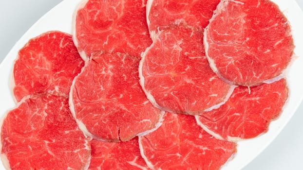 Top view of some raw beef on a plate over white background