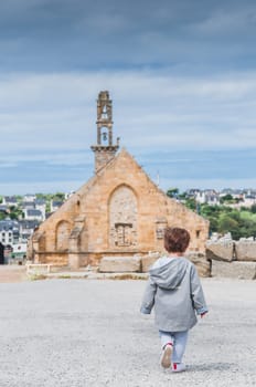 Child walking in front of Notre Dame de Rocamadour church in Camaret-sur-mer, Finistere, Brittany, France