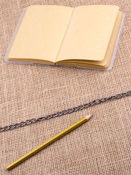 Pencil and notebook with a chain in the middle  on spiral notebooks
