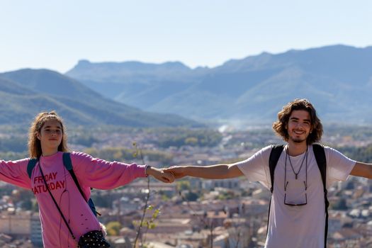 Young man and girl hiking. They climbed to the top of the mountain and joyfully held hands.