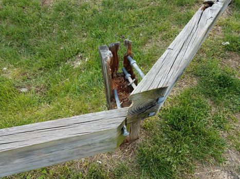 broken or weathered or worn wood fence with metal screws and green grass