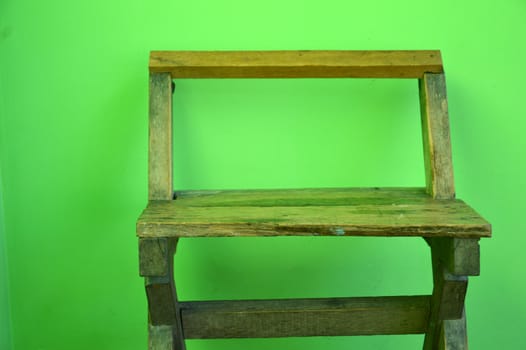 old used wooden chairs on the green wall