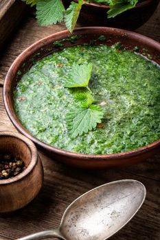 Nettle cream soup on wooden background.Soup with fresh nettles