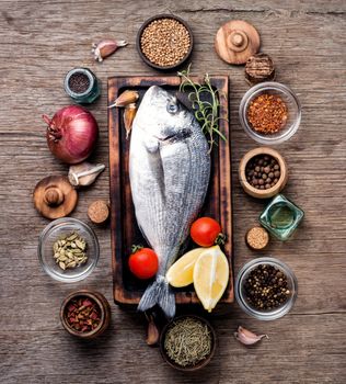 Fresh fish with ingredients for cooking.Fresh dorado fish on wooden cutting board