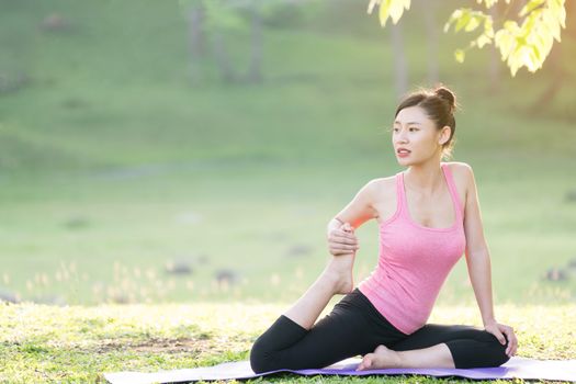 young beautiful asian woman practicing yoga  in the garden