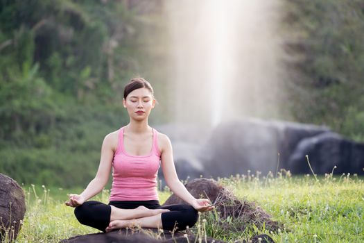 young beautiful asian woman practicing yoga  in the garden