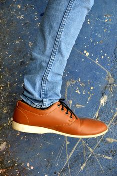 leather shoes with jeans on concrete wall