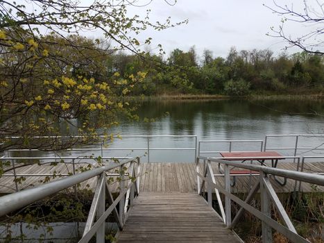 wooden walkway or ramp floating platform and picnic table and lake with trees