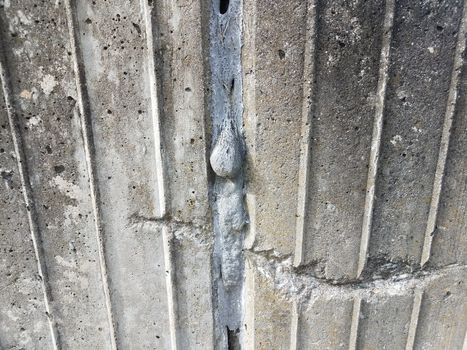 grey cement wall with scratch and dripping filler in a crack