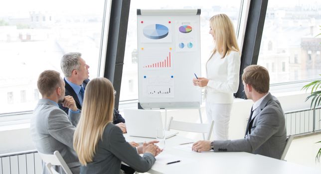 Businesswoman pointing at a chart on a whiteboard during business meeting
