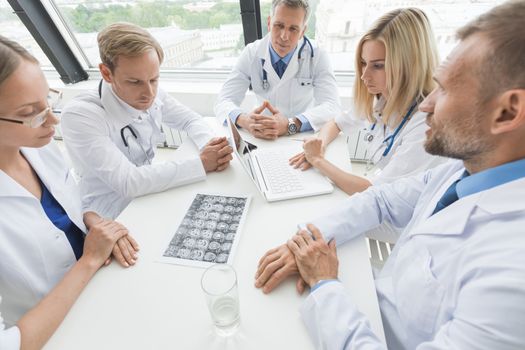 Team of doctors discuss brain scan sitting around the table