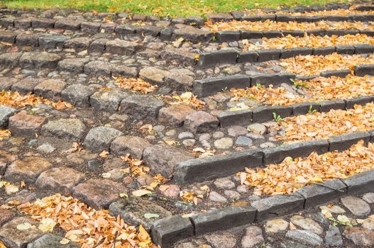 A staircase of stone with many autumn leaves