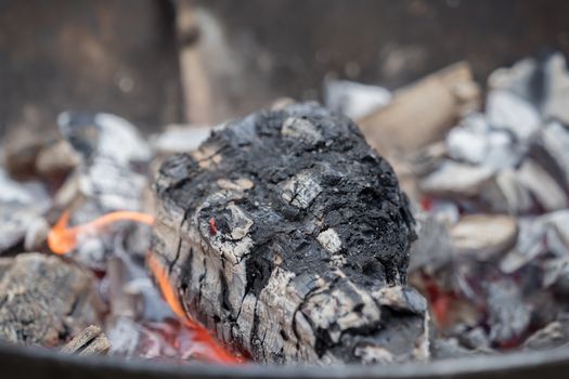 Hot charcoal burns in the grill with embers