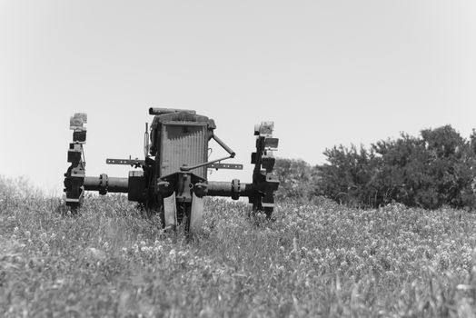 Vintage tone old tractor and Bluebonnet blossom at rural farm in Bristol, Texas, USA. Wildflower blooming in meadow with rustic wagon, countryside landscape