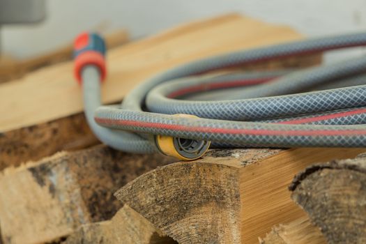 A garden hose lies on a pile of wood