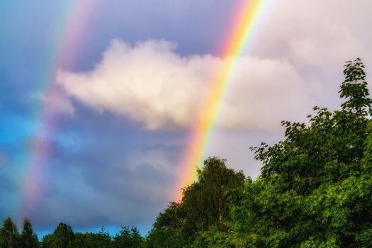 Rainbow after rain in a cloudy sky among dramatic clouds.