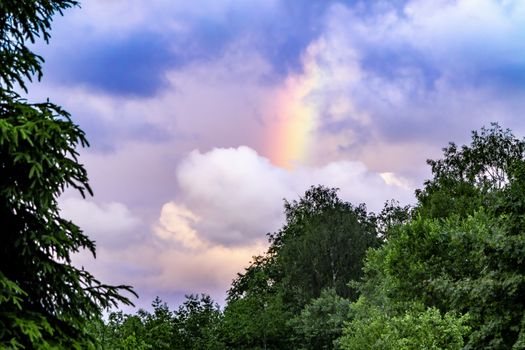 Rainbow after rain in a cloudy sky among dramatic clouds.