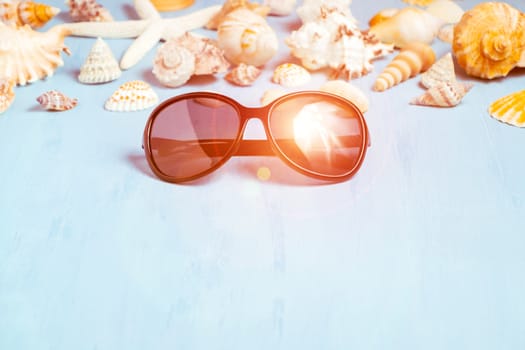 Blue sea background with sunglasses and seashells, summer holiday and vacation time concept.